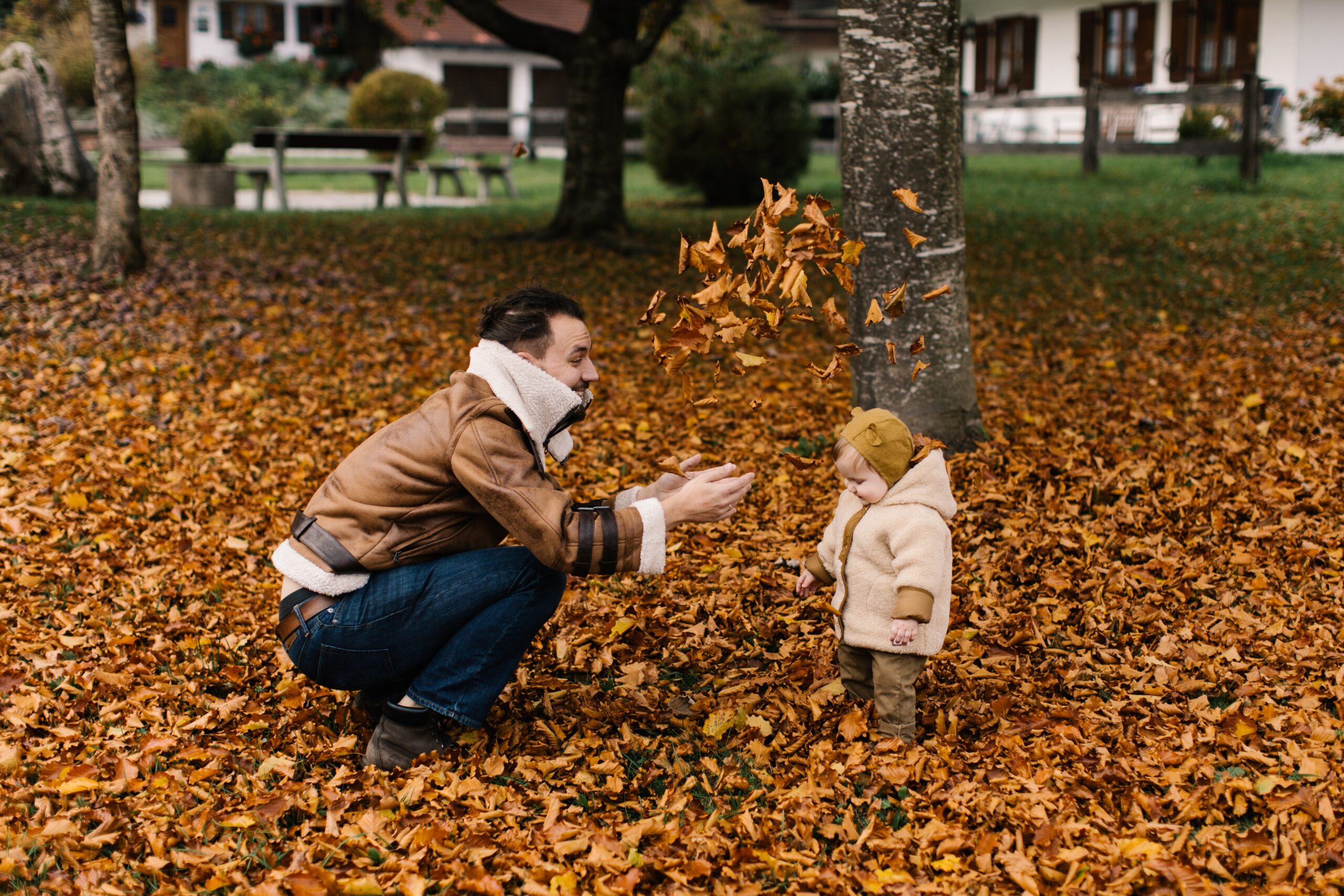 man throwing leaves with daughter